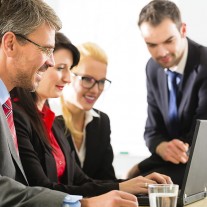 Businesspeople look at a laptop