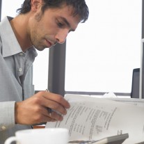 Businessman using PCs and looking at documents, close up, side view