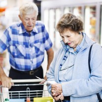 Senior couple check shopping list in supermarket aisle