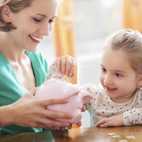 Mother and daughter putting coins into piggy bank